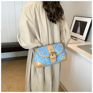 Detailed view of retro denim shoulder bag with khaki leather trim and metallic buckle