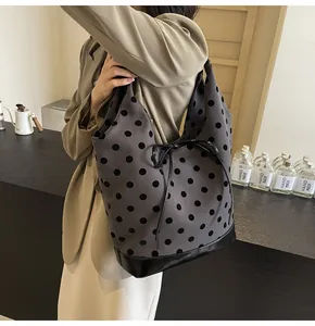 Detail showing grey polka dot tote bag with black leather bottom and bow drawstring