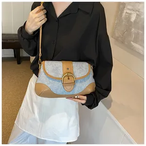 Close-up of vintage denim hobo bag featuring brown leather trim and a gold metal buckle