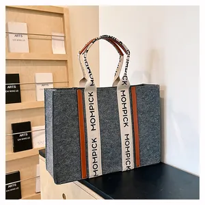 Detail of grey felt tote bag showing durable fabric and MOMPICK lettered handle straps