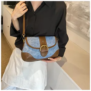 Detail of vintage denim shoulder bag with brown leather trim and large gold buckle