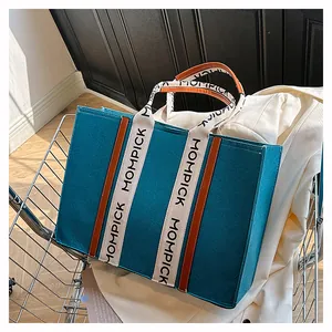 Detailed view of teal felt tote bag with brown leather accents in a shopping cart