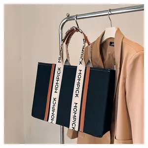 Detail of MOMPICK tote bag showing black canvas texture and durable beige lettered strap
