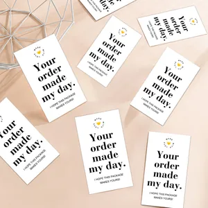 Flat lay of white business thank you cards with heart logo on a beige background