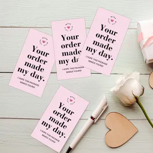 Close-up of pink business thank you card with artistic typography on a green wooden background