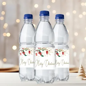 Close-up of Merry Christmas water bottle labels with gold script and berry designs