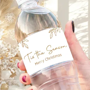 Close-up of hand holding a water bottle with gold 'Tis the Season' Christmas label sticker