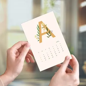 Minimalist 2026 wall calendar card featuring letter A and April floral design in hands