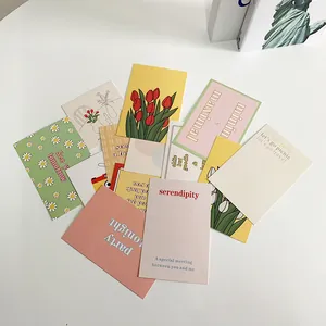 Artistic collage of tulip and geometric postcards scattered on a white desk backdrop