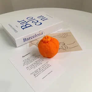 Realistic orange shaped aromatherapy candle with peel texture on a minimalist white desk