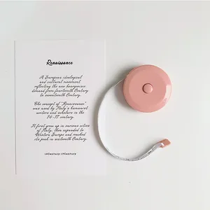 Macaron pink retractable sewing tape measure for body measurement on white surface