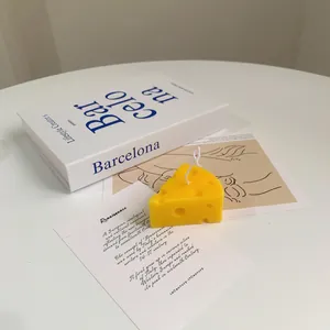 Realistic cheese shaped soy wax scented candle on a desk with artistic books
