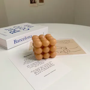 Detailed view of cube bubble soy wax candle in soft orange color on a white table