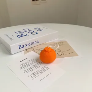 Realistic orange-shaped scented soy candle with citrus texture on a minimalist artistic background