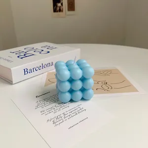 Detailed macro view of a sky blue cube bubble candle made of soy wax on a white desk