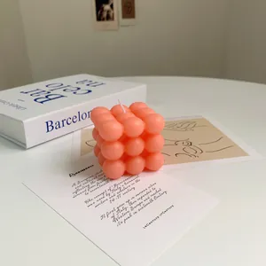 Close-up of a pink bubble cube candle with a white wick and textured surface