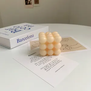 Macro detail of cube-shaped soy wax candle with artistic book and card setup