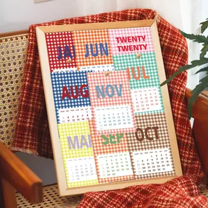 Detail van vintage geruite kalenderkaarten 2026 in houten lijst op een rotan stoel