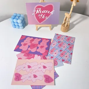 Set de cartes postales de lapin rose mignon et de cartes d'art de cœur sur un bureau blanc