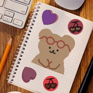Cute brown bear and heart stickers set on a white notebook with a desk background