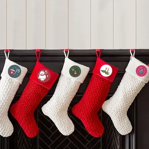 Set of knitted Christmas stockings with numbered advent tags hanging on a fireplace