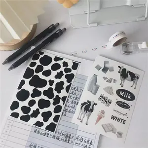 Close-up of cow print stickers, milk patterns, and washi tape with 0.5mm black gel pens