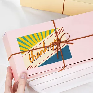 Dettaglio scatola regalo rosa con biglietto di ringraziamento e fiocco marrone elegante