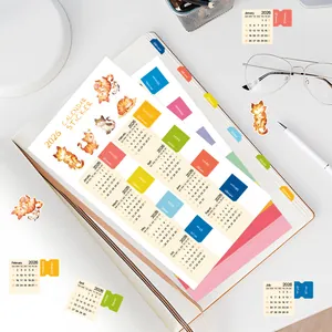 Vista macro degli adesivi calendario 2026 con illustrazioni di gatti su un taccuino d'appunti