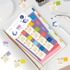 Primo piano degli adesivi calendario 2026 con linguette colorate su un taccuino