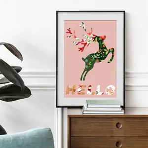 Framed Christmas reindeer poster with Hello lettering on a wooden cabinet for home decor
