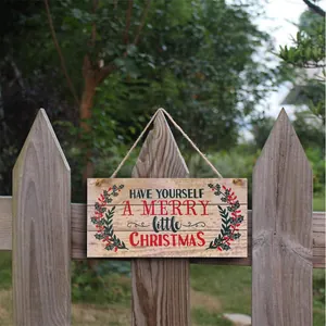 Weihnachtliches Holzschild am Gartenzaun mit festlichem Text und Stechpalmenbeeren-Dekor