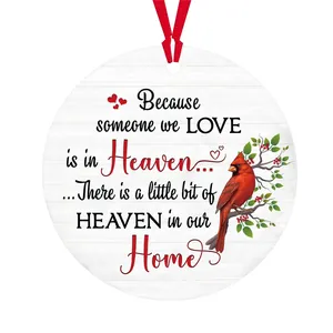 Close-up of circular acrylic ornament featuring a cardinal bird and red ribbon hanger
