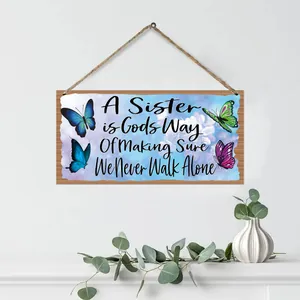 Rustikales Holzschild mit Schmetterlingsmotiv und Spruch an weißer Wand hängend