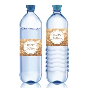 Macro detail of black and gold Happy Birthday water bottle labels with glitter texture