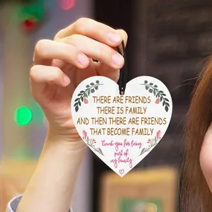 Detail of heart-shaped wooden plaque featuring floral prints and sentimental English quotes