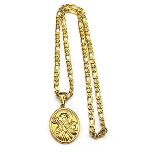 Détail du pendentif médaille Saint Benoît doré avec chaîne Figaro sur fond blanc éclatant