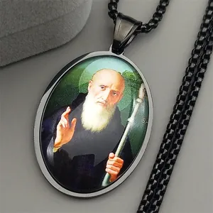 Macro view of black stainless steel oval pendant with religious saint portrait and link chain