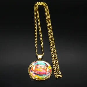 Macro shot of gold football pendant with colorful art on reflective black background