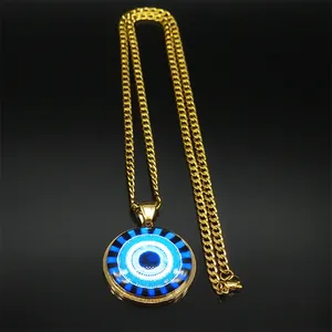 Macro detail of golden Cuban chain with blue Evil Eye pendant on black background