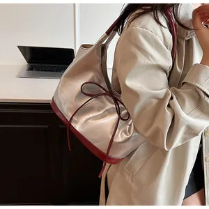 Silver PU leather tote bag with red bow detail shown on shoulder for a stylish look