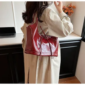 Detail of burgundy patent leather tote bag with stylish bow accent and glossy finish