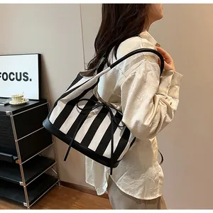 Detail of the bow ribbon and black and white striped canvas on the shoulder tote bag