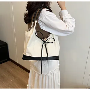 Detail of minimalist tote bag with chic black bow and contrast leather stitching