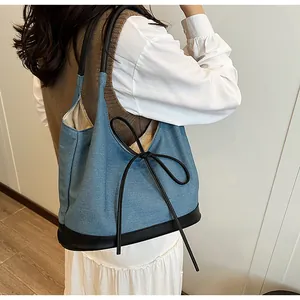 Lifestyle view showing the spacious denim shoulder bag with a stylish black bow detail