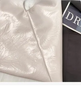 Close-up of a pearlescent cream shoulder bag featuring detailed stitching and pleated leather