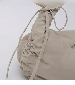 Detail of beige pleated dumpling bag showing nylon texture and white stitching details