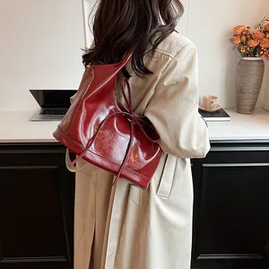 Elegant deep red glossy PU tote bag with bow detail shown on shoulder in office setting