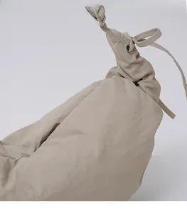 Detail of beige pleated nylon dumpling bag showing silver eyelets and drawstring closure