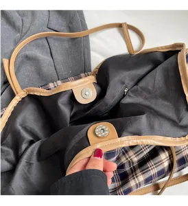 Macro view of plaid tote bag featuring magnetic snap closure and leather trim