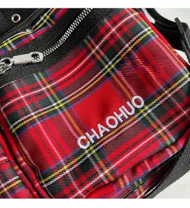 Macro detail of red plaid tote bag featuring white letter embroidery and metal zipper